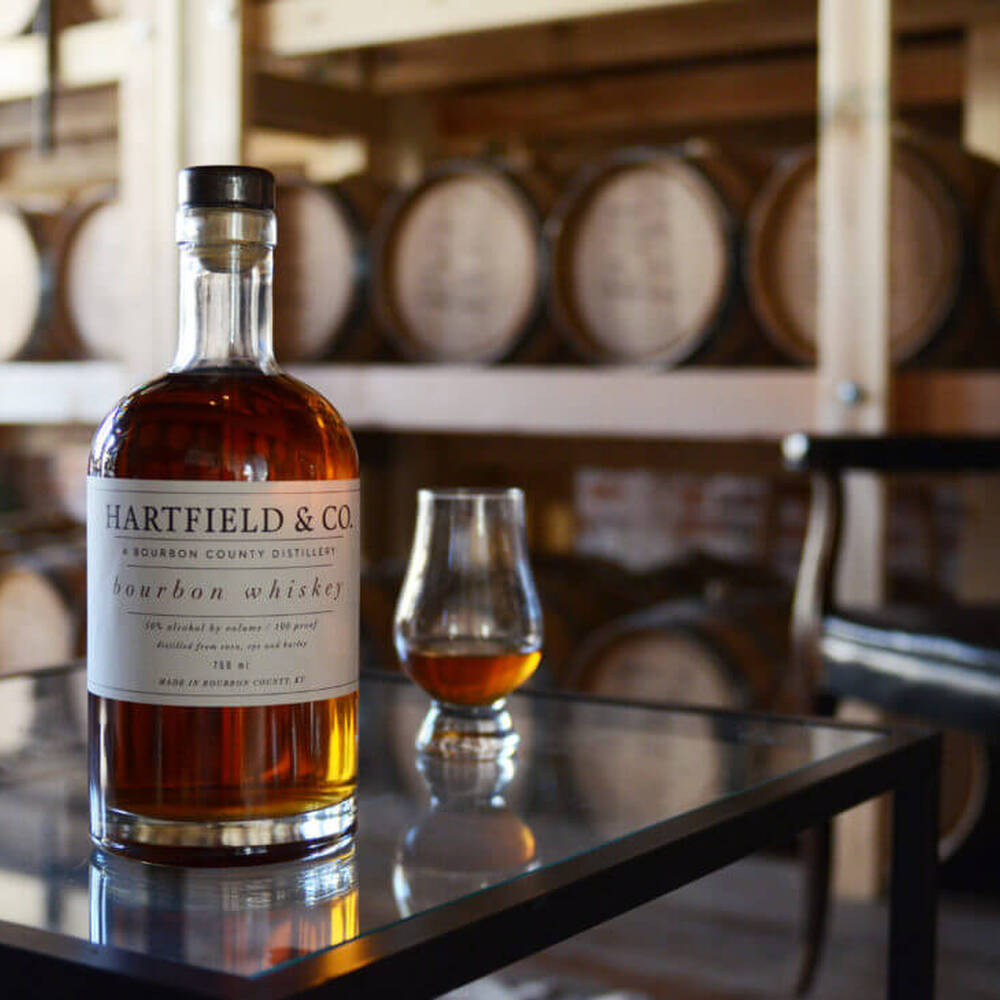 bottle and glass in front of barrels