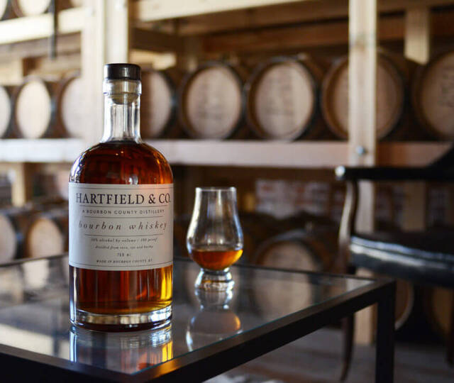 bottle and glass in front of barrels